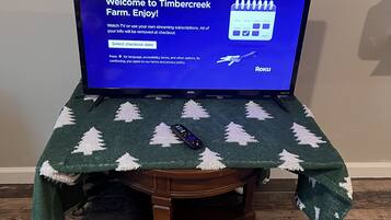 Un televisor sobre una mesa de madera con mantel navideño.