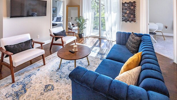 Una sala moderna con un sofá seccional azul, una mesa de centro de madera y un sillón blanco.