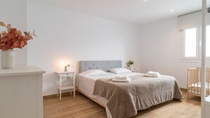 A minimalist bedroom with a bed, bedside tables, a nightstand, a crib, and a window. - Gorgeous home in Mijas (Mijas)