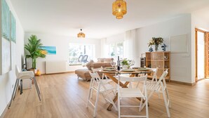 A spacious living area with a round glass table, white chairs, a beige sofa, and a wooden bookshelf. - Gorgeous home in Mijas (Mijas)