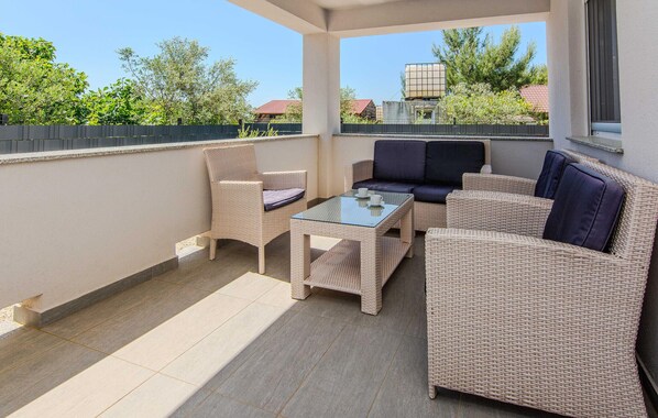 A covered outdoor seating area with wicker furniture and a glass-top table.
