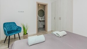 Een slaapkamer met een bed, een blauwe stoel, een plant en een kledingkast.