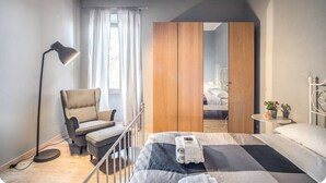 Une chambre à coucher comprenant un lit, une chaise, un bureau, une lampe et une armoire.