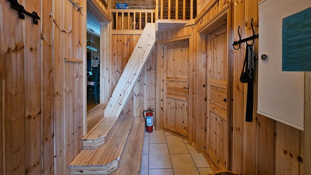 A narrow wooden hallway with a wooden staircase leading to a loft area.
