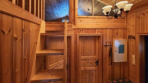 A wooden interior with a staircase, a door, and a light fixture.