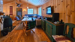 A cozy cabin interior with a wooden interior, a sofa, a television, and a mounted animal head.