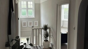 Een gang met een potplant, geïllustreerde inspirerende citaten en een trap die naar een andere kamer leidt.