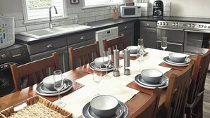 Een moderne keuken met een eettafel voor zes personen, voorzien van een magnetron, oven en koffiezetapparaat.