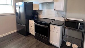 A modern kitchen with a black refrigerator, a coffee maker, a microwave, and a water dispenser.