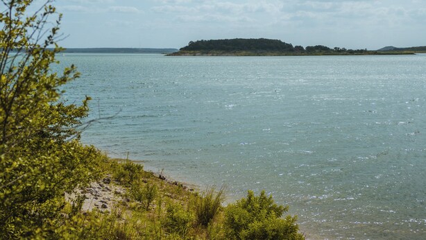 Un lago calmo con una piccola isola all'orizzonte.