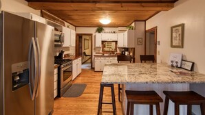A modern kitchen with a large island, stainless steel appliances, and wooden flooring. - Charming Country Home w/Character of the Adirondacks (Lake Placid)
