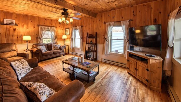 A cozy cabin interior with wooden walls and floors, a large TV, and a fireplace. - Charming Country Home w/Character of the Adirondacks (Lake Placid)