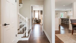 A spacious hallway with a staircase leading to a living area and kitchen. - Kid-Friendly 4 Bedroom Home w/ Heated Private Pool (Overland Park)