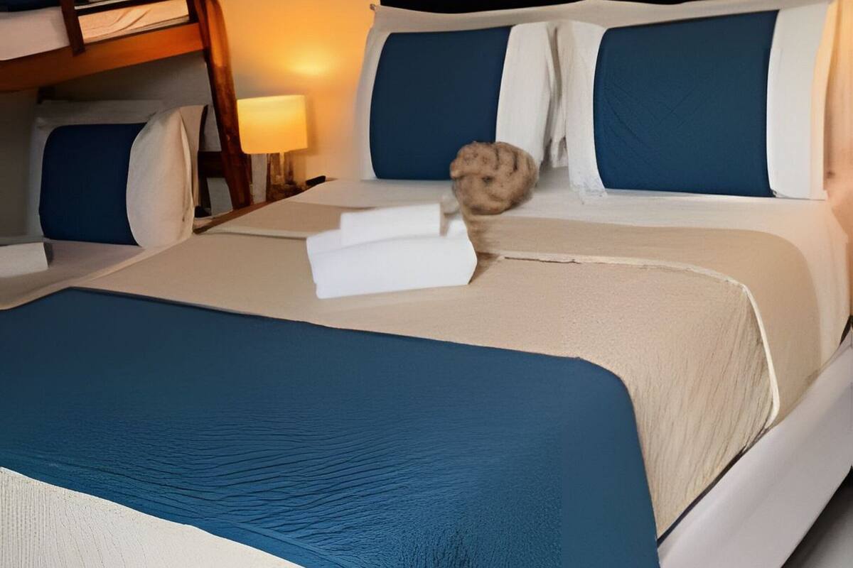 A neatly made bed with blue and white bedding, a wooden headboard, and a small round rug.