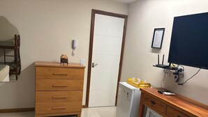 Un angolo cottura con un armadietto in legno, un frigorifero, un forno a microonde e un televisore fissato al muro.