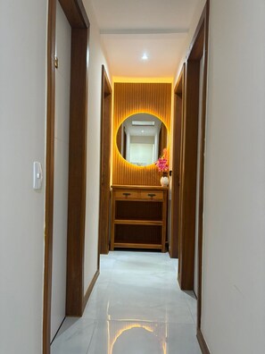 Un couloir avec une coiffeuse en bois, un miroir et une petite étagère.
