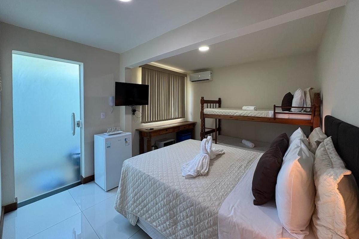 Una habitación de hotel con cama, escritorio, televisión y aire acondicionado.