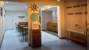 A spacious kitchen with a water dispenser, a dining area with a table and chairs, and a staircase leading to another level. - Suítes Brisa do Mar (Búzios)