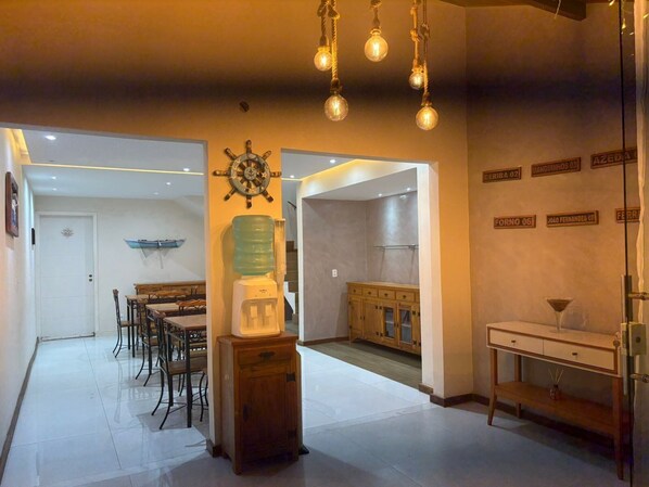 Una cocina amplia con dispensador de agua, un comedor con mesa y sillas, y una escalera que sube a otro nivel.