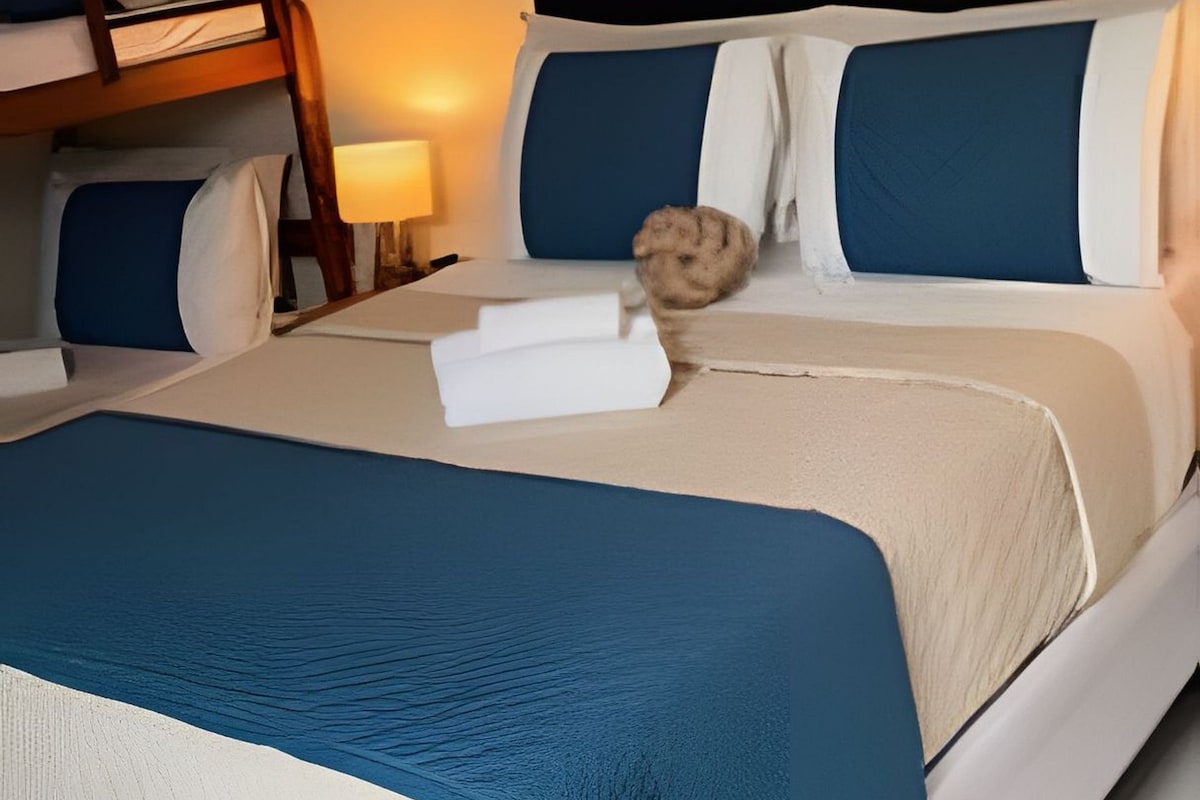 Una cama bien hecha con ropa de cama azul y blanca, un cabecero de madera y una alfombra redonda pequeña.