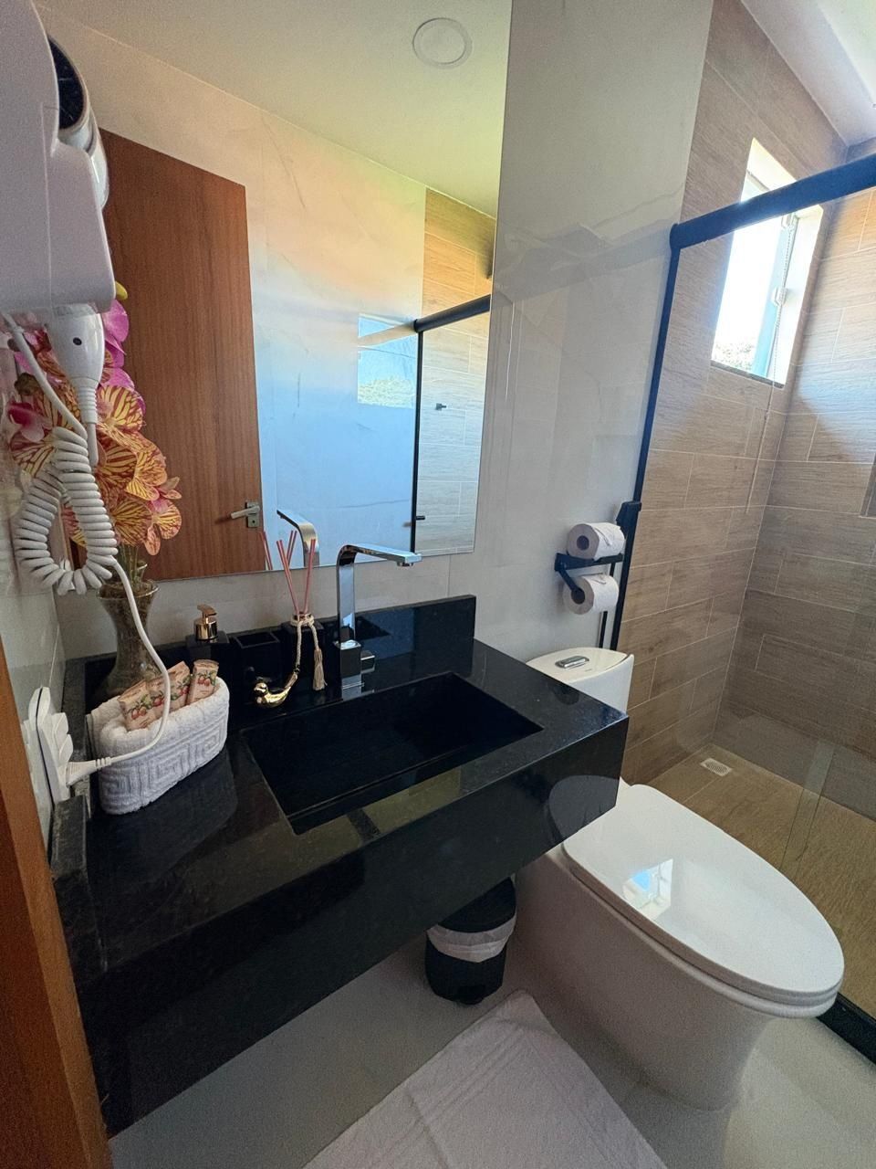 A modern bathroom with a black sink, white toilet, and a shower area.