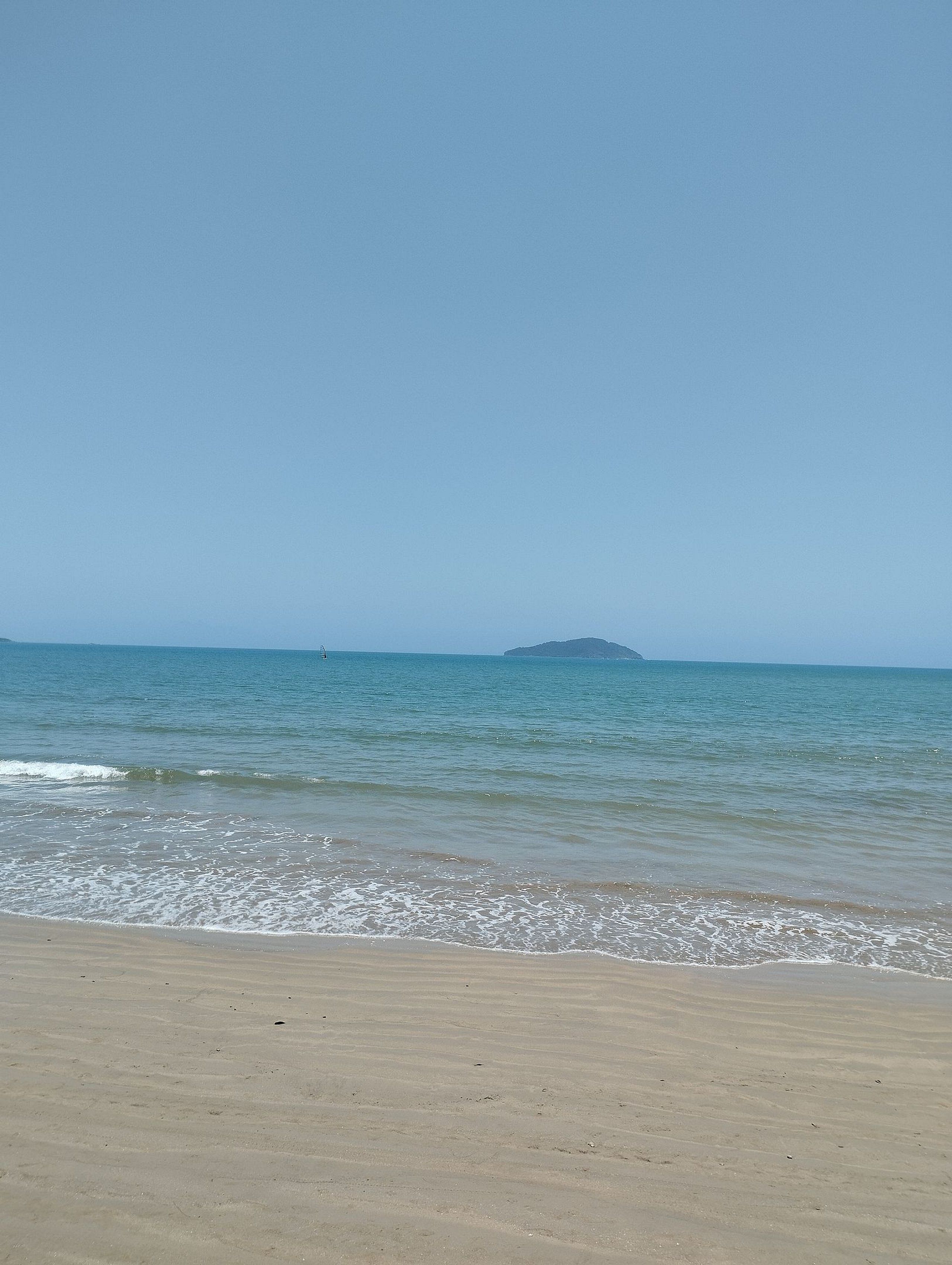 A beach with a clear sky and calm sea.