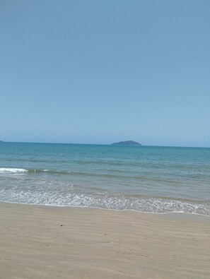 Ein Strand mit blauem Himmel und ruhigem Meer.