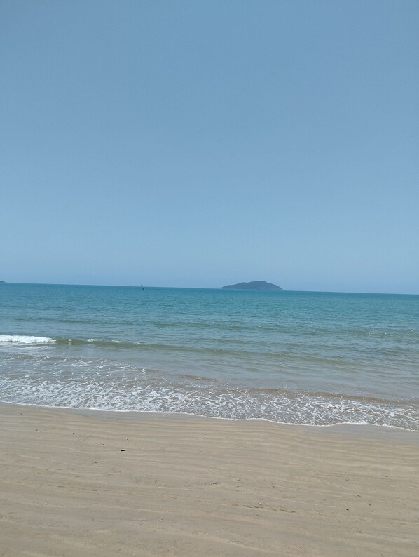 Una playa con cielo despejado y mar tranquilo.