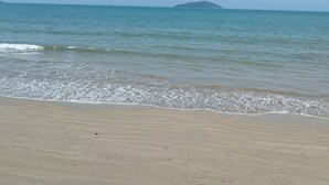 A beach with a clear sky and calm sea. - Suítes Brisa do Mar (Búzios)