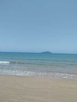 Uma praia com céu claro e mar calmo.