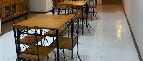 A dining area with wooden tables and chairs, a wooden cabinet, and a wall-mounted anchor decoration.