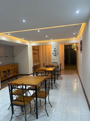 A dining area with wooden tables and chairs, a wooden cabinet, and a wall-mounted anchor decoration. - Suítes Brisa do Mar (Búzios)
