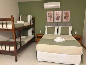 A room with a bunk bed, a single bed, and a wall-mounted air conditioner. - Suítes Brisa do Mar (Búzios)