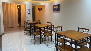 Una zona pranzo con tavolo e sedie, una parete con un quadro e una tenda.