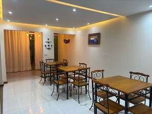 Ein Essbereich mit Tisch und Stühlen, einer Wand mit einem Gemälde und einem Vorhang.