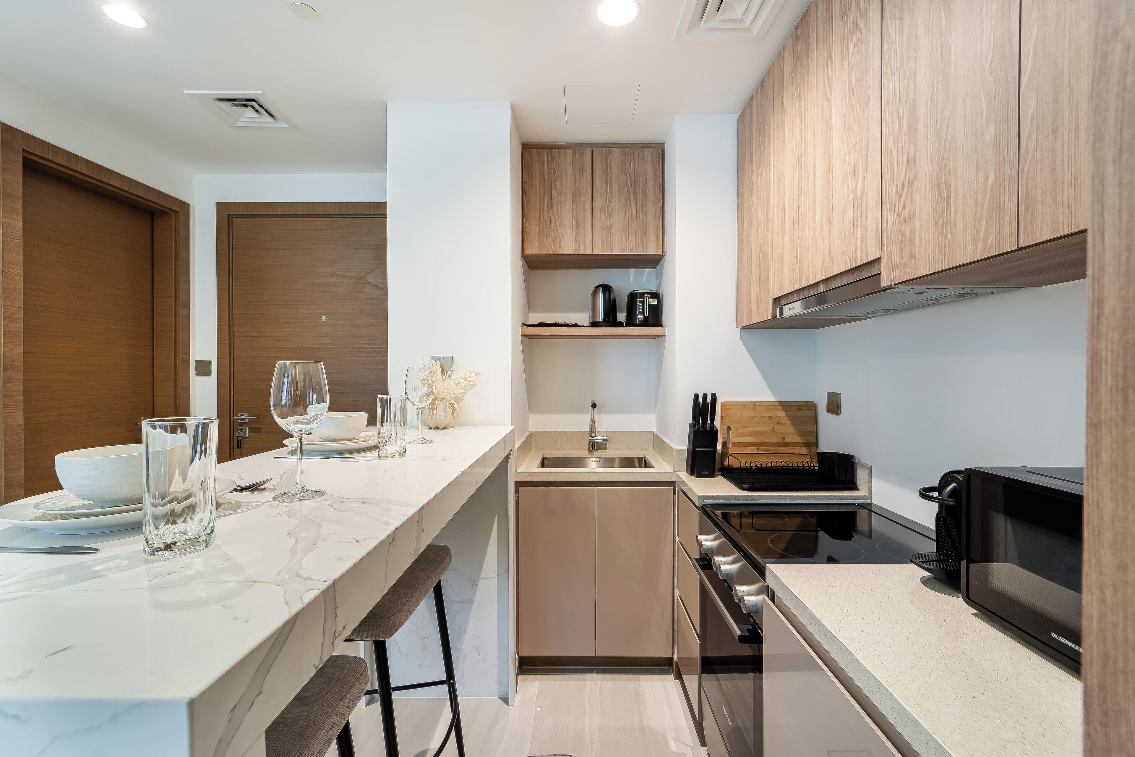 A modern kitchen with a marble countertop, wooden cabinets, and stainless steel appliances.