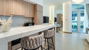 A modern kitchen with a marble countertop, wooden cabinets, and two bar stools.