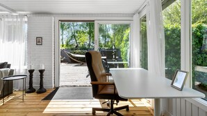 A modern room with a white table, a leather chair, and a view of an outdoor deck and garden. - 3 bedroom beautiful home in Gilleleje (Gilleleje)
