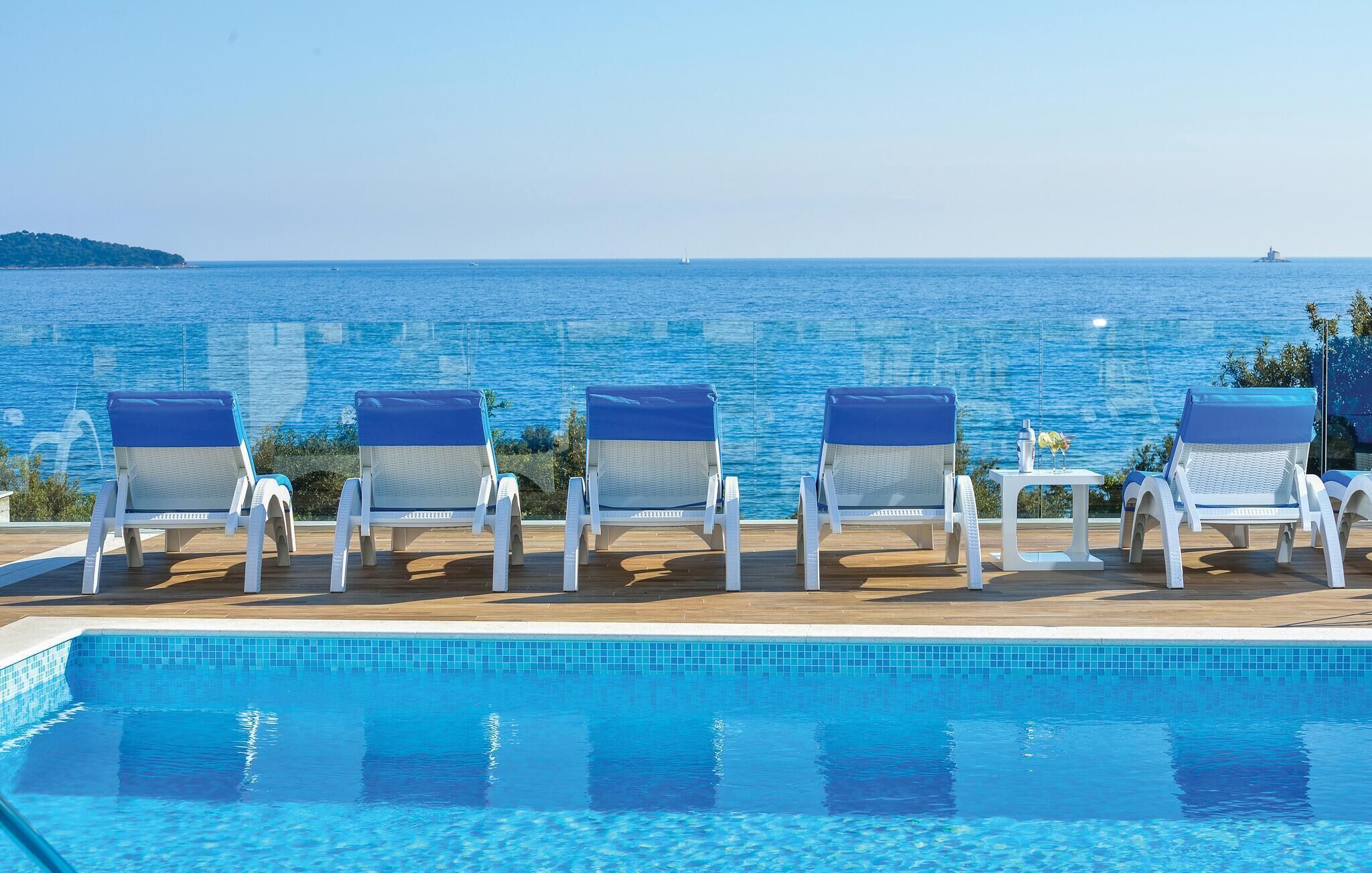 Un espace aménagé au bord de la piscine, avec des chaises longues et une vue sur la mer.