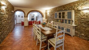 A dining area with a wooden table, white chairs, and a stone wall.