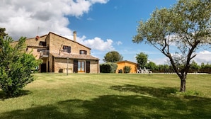 A stone house with a large lawn and a tree.