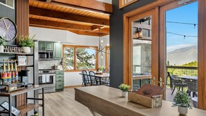 Una cocina moderna con vigas de madera, un comedor con un amplio ventanal y vistas al exterior.