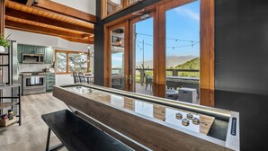 Una cocina moderna con vigas de madera, una isla grande y vistas a una terraza y montañas.