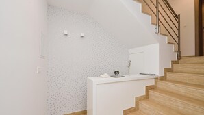 Una escalera con peldaños de madera y una pared blanca con un patrón discreto.