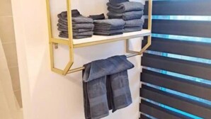 Ein Badezimmer mit Handtuchhalter, gefalteten Handtüchern und Toilettenpapierhalter.