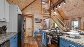 A kitchen with wooden walls, a stainless steel refrigerator, granite countertops, and a gas stove. - Large Family Getaway Cabin w/Hot Tub + Game Room - Minutes to Blue Ridge (Blue Ridge)