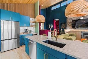 Eine moderne Küche mit blauen Schränken, Edelstahlgeräten und einer großen Kochinsel mit Spüle.