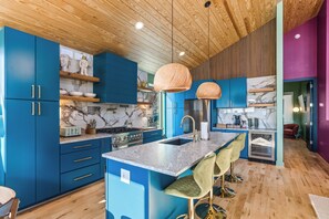 Eine moderne Küche mit blauen Schränken, einer Marmor-Spritzschutzleiste und einer Holzbalkendecke.