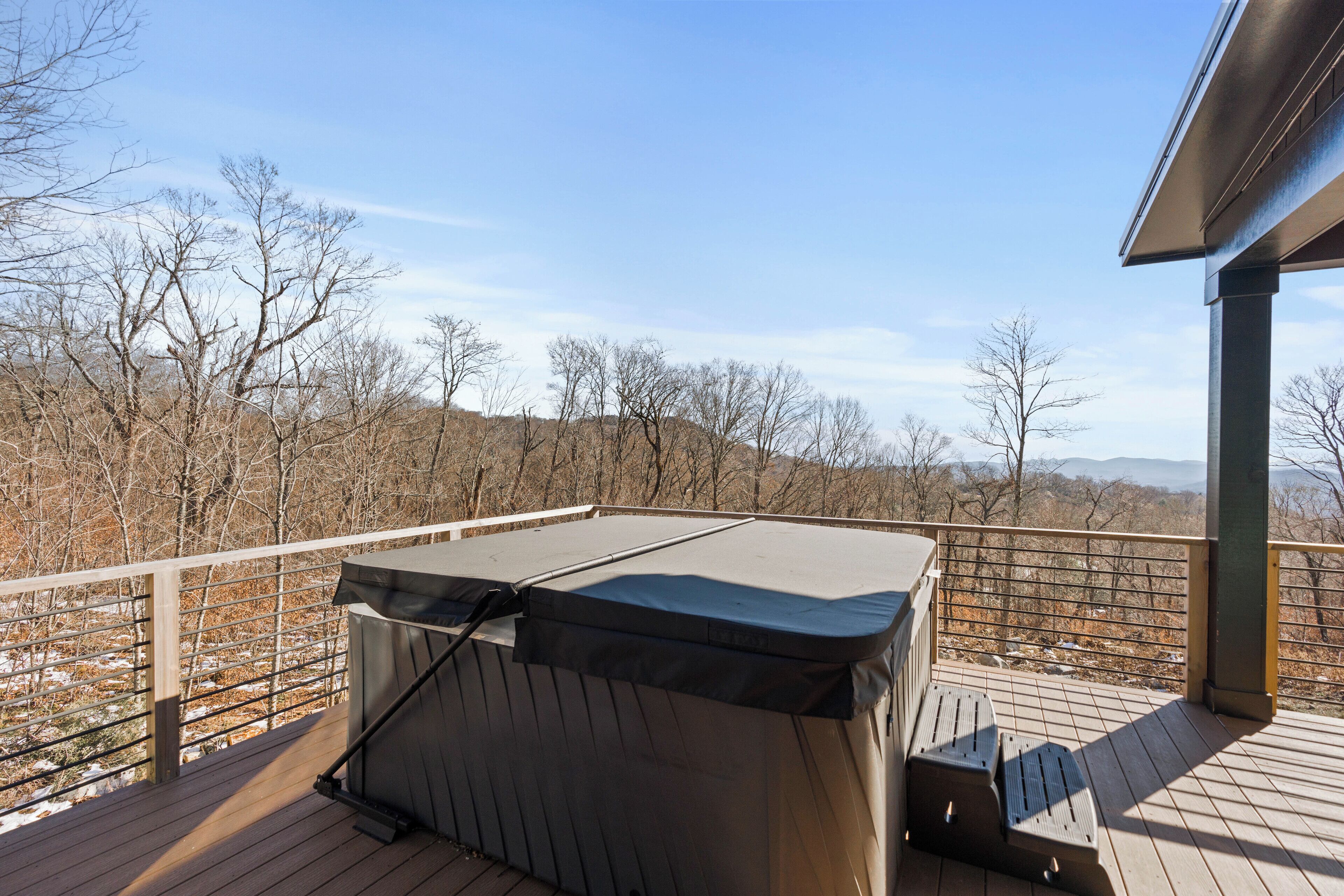 A hot tub on a wooden deck with a view of a mountainous landscape.