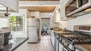 Une cuisine moderne dotée d’appareils électroménagers en acier inoxydable, d’un plafond en bois et offrant une vue sur l’extérieur.